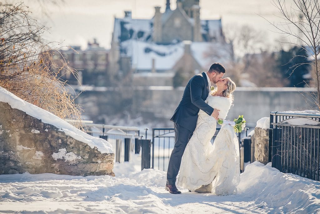 Bride and groom kissing in mill race park in the winter in Cambridge Ontario