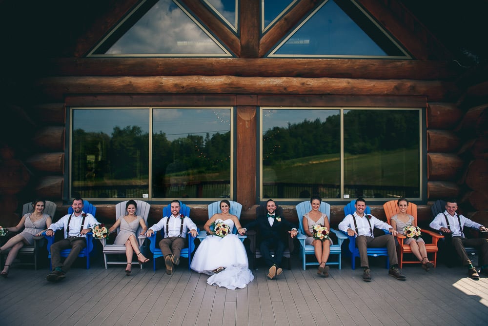 wedding party sitting on muskoka chairs on deck at pine valley chalet