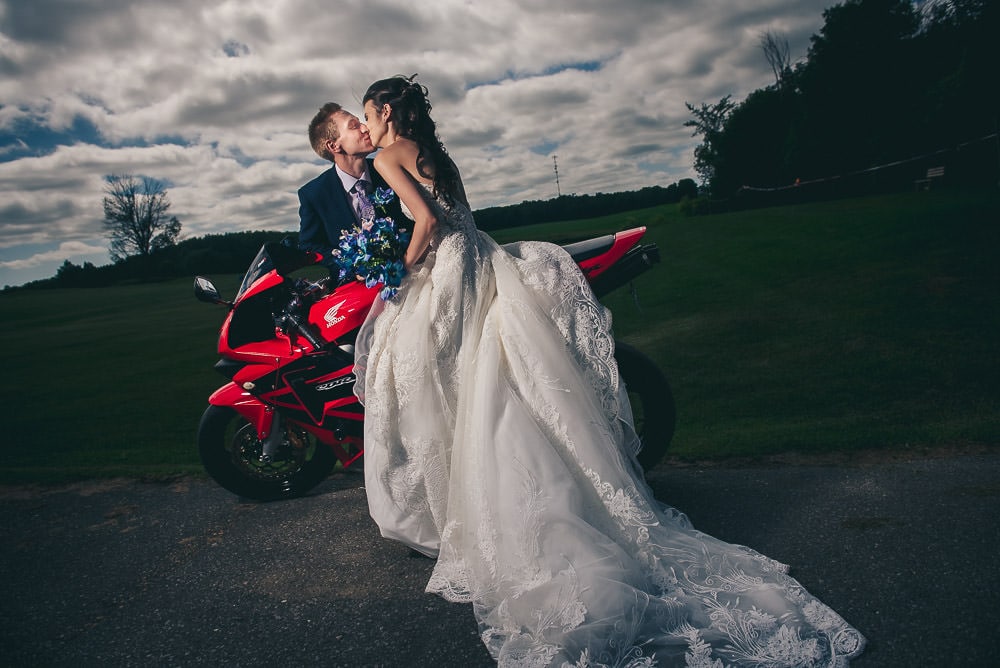 bride and groom kissing on motorbike at their wedding at Mitchel Golf club