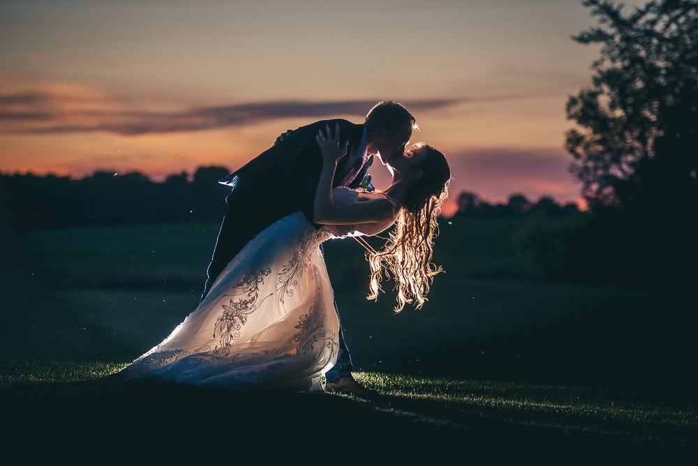 sunset wedding photo bride and groom doing dip kiss at Mitchel golf course
